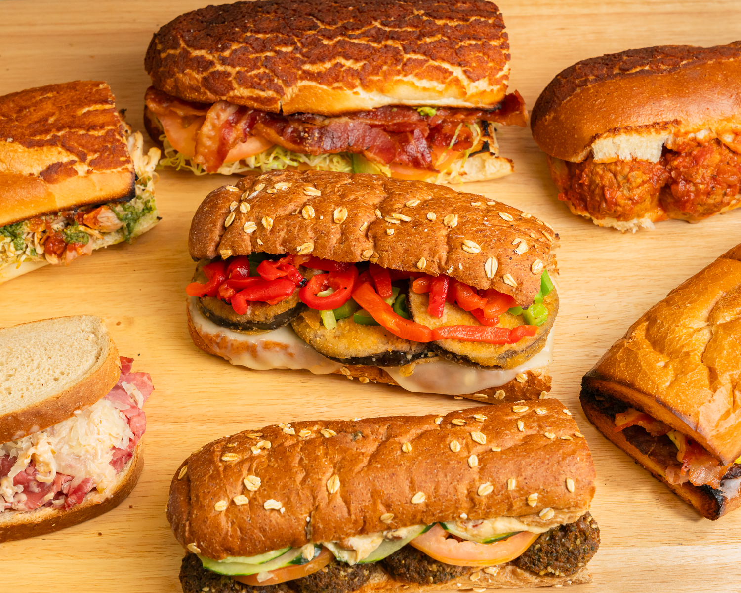 Freshly made deli sandwich with layered meats, cheese, lettuce, and tomato on rustic bread